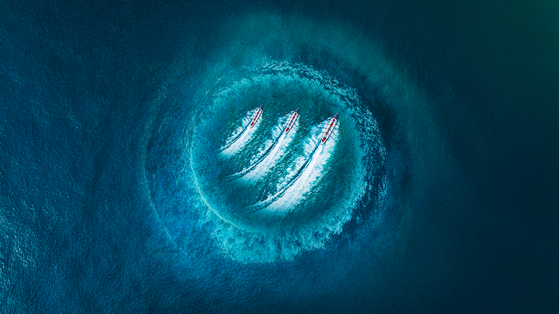 Aerial view of boats leaving wake patterns in blue water