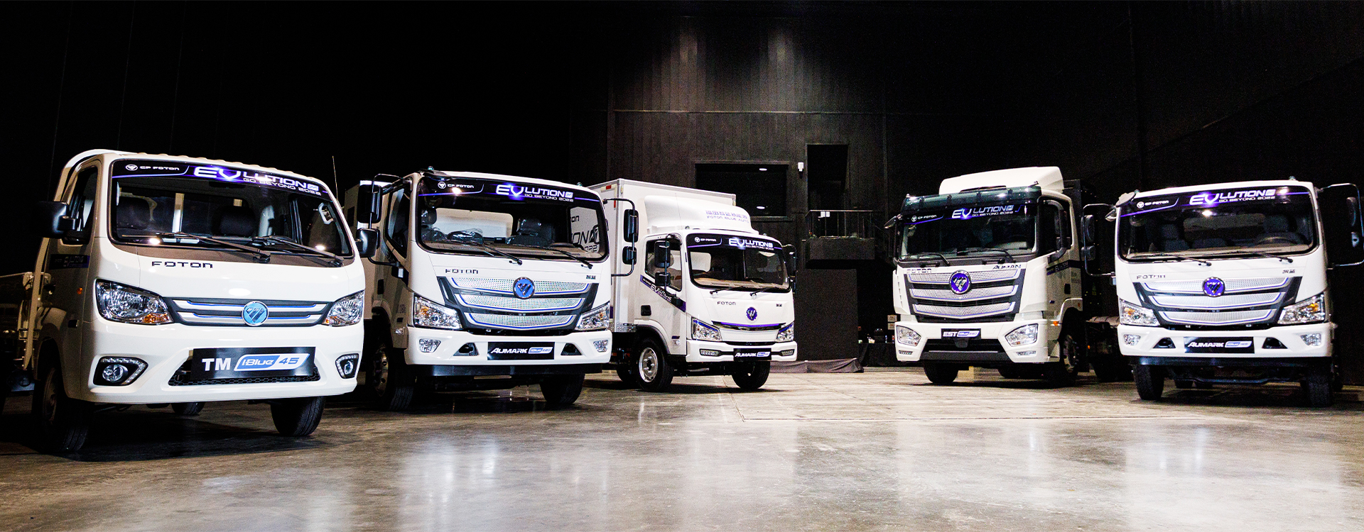 Five FOTON EVolutions trucks parked in a dark showroom